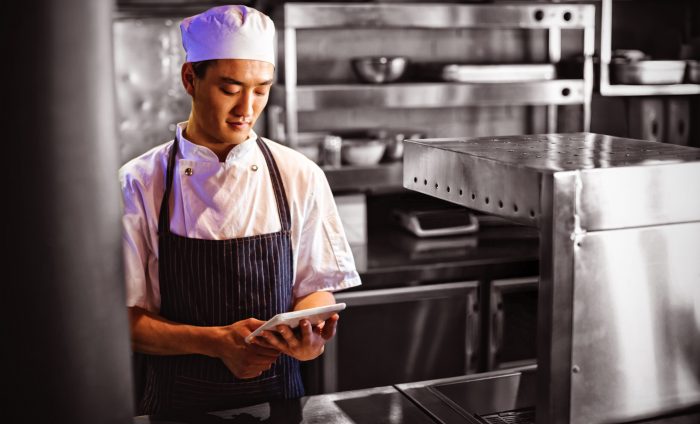 Smiling chef using digital tablet in the commercial kitchen